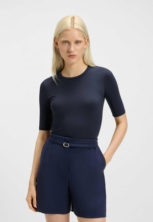 Haut bleu marine à manches courtes en tissu lisse, assorti à un short bleu marine taille haute avec une ceinture à boucle en argent.