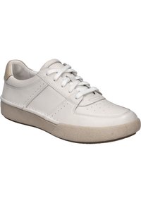 Valkoinen nahkainen tennari, jossa on pyöreä kärki, rei'itettyjä yksityiskohtia kärjessä ja beige rakennekuminen pohja. Mukana samansävyiset nauhat ja korostukset.