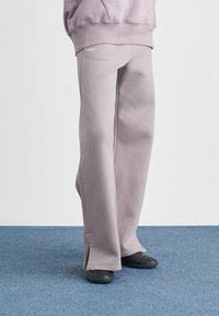 Ανοιχτό μοβ φόρμα από μαλακό ύφασμα, με άνετη εφαρμογή, ραφές διακοσμητικές και ανοίγματα στο πλάι στους αστραγάλους.