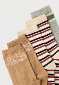 Τέσσερα ζευγάρια κάλτσες: μπεζ με λευκά γράμματα, εκρού με μπορντό και μαύρες ρίγες, γκρι με πράσινες και μαύρες ρίγες, και ανοιχτό καφέ.