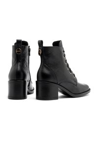 Czarne skórzane botki za kostkę o strukturalnym wykończeniu, z przeszywaniem z przodu, zamkiem błyskawicznym z boku i grubym obcasem. Posiadają złote akcenty metalowe.