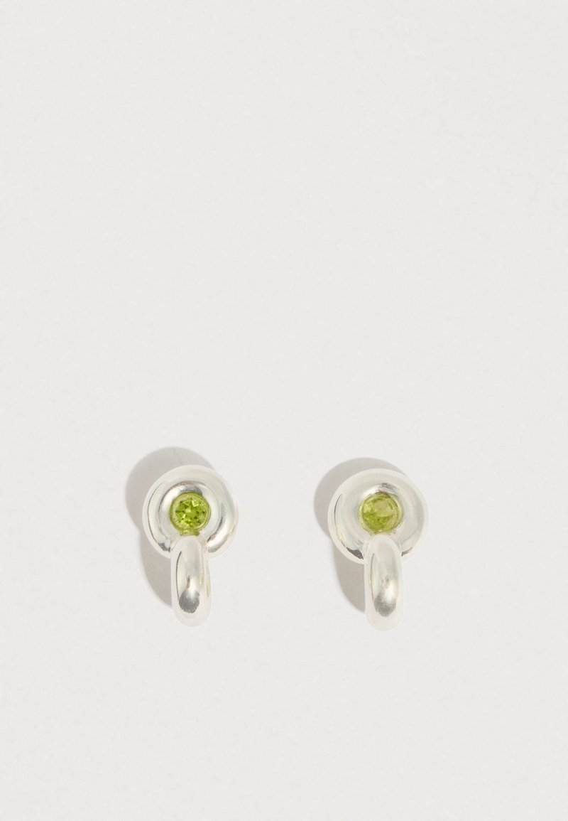 Boucles d'oreilles en argent avec un design circulaire et une pierre précieuse verte au centre, présentant une texture lisse et une finition polie.