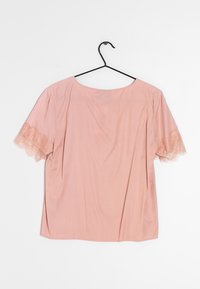 Blusa rosa claro de mangas cortas, con ribete de encaje en las mangas, cuello redondo y corte recto, hecha de una tela suave.