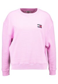 Rosa sweatshirt med långa ärmar, ribbade manschetter och nederkant. Har en liten Tommy Jeans-logopatch på vänster bröst. Mjuk tygtextur.