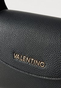 Czarna skórzana torba o fakturowanej powierzchni. Złote logo "VALENTINO". Kompaktowy design z zaokrąglonym kształtem i gładkimi detalami.