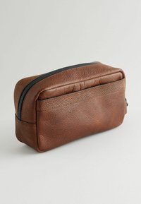 Pochette in pelle marrone con superficie testurizzata, forma rettangolare e zip nera a contrasto lungo il bordo superiore. Accentuata da cuciture sottili.