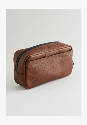 Ruskea nahkapussi, jossa on teksturoitu pinta, suorakulmainen muoto ja kontrastivälinen musta vetoketju yläreunassa. Korostettu hienovaraisilla saumoilla.