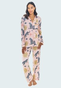 Rosa pyjamaset med svarta och gyllene leopardmönster, soler och himmelska design. Tillverkat av mjukt tyg med en knäppskjorta och matchande byxor.