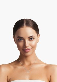 Sølv halskæde med en rund vedh�æng, der har en delikat kæde. Modellen har skulderlangt hår og en neutral baggrund.