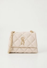 Μπεζ καπιτονέ δερμάτινη τσάντα χειρός με χρυσή αλυσίδα για λουράκι και χρυσά διασταυρούμενα αρχικά γράμματα στην μπροστινή πτερύγιο.