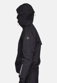 Veste d'extérieur noire avec une capuche ajustée, fermeture éclair à l'avant, ourlet ajustable et accents de logo sur les manches. Fabriquée en matériau résistant à l'eau.