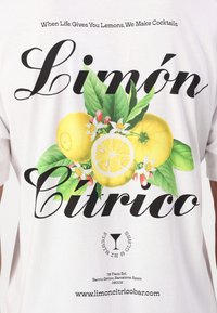 Hvid bomulds T-shirt med et farverigt citronmotiv, grønne blade og teksten "Limón Cítrico" i fed sort skrift.