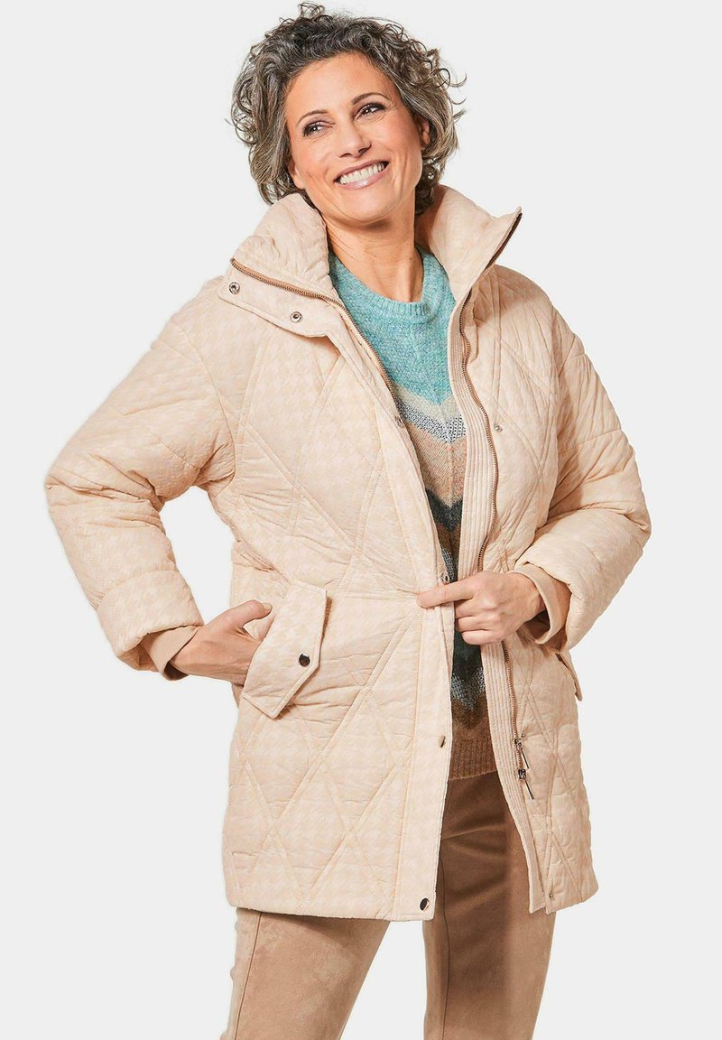 Beige gestepptes Jacket mit hohem Kragen, Frontreißverschluss, Druckknöpfen und Seitentaschen, mit einem Rautenmuster und weicher Textur.