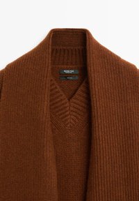 Cardigan in lana bronzo con una texture a coste, dotato di scollatura a V profonda e ampi rever. Le etichette indicano il marchio e la composizione del materiale.