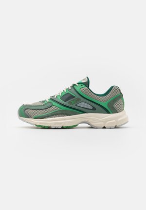 Baskets de sport en mesh gris et vert avec lacets blancs et semelle épaisse blanche, vues de côté sur un fond uni.