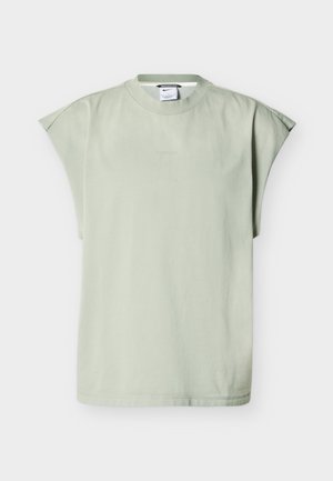 Világoszöld, rövid ujjú, kerek nyakú póló laza vállrésszel és Nike logóval a gallércímkén, semleges háttér előtt bemutatva.