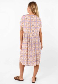 Robe à motif floral avec des manches courtes, présentant une taille froncée. Les couleurs incluent le violet pastel, le pêche et la crème. Tissu léger.