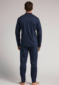 Conjunto de camiseta de manga larga y pantalones en azul marino, hecho de una suave tela, que presenta un ajuste relajado y un diseño simple. Textura suave sin patrones.