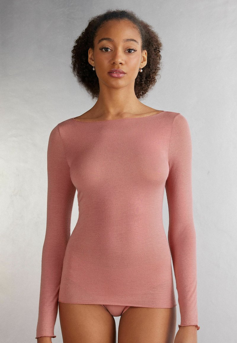 Langsleeve top in een stoffige rozenkleur, gemaakt van een zachte stof. Beschikt over een off-shoulder halslijn en een getailleerd silhouet. Soepele textuur.