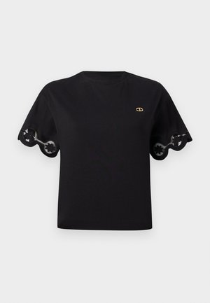 Black cotton t-shirt with short flared sleeves featuring a scalloped lace trim. Small gold logo on the chest. Simple, classic design.