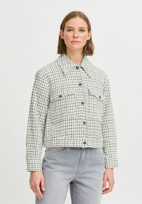 Hvid- og marineblå ternet jakke med krave, frontknapper og to brystlommer. Stoffet har en tekstureret overflade.