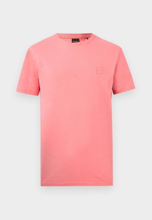 Egyszínű rózsaszín rövid ujjú, kerek nyakú póló kicsi négyzet alakú logópattintással a bal mellrészen és fekete márkázott nyakcímkével.