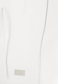 Weiße Lederhandtasche mit glatter Textur, schlankem Design und einem kleinen Metall-Logo-Plakette. Inklusive Nachverarbeitung entlang der Kanten.