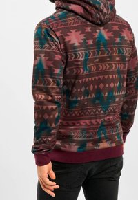 Sudadera con capucha de diseño estampado en marrón, azul verdoso y rojo. Incluye puños y dobladillo acanalados, material de felpa y un motivo geométrico tribal.