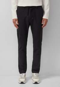 Donkergrijze tapered broeken van een zachte stof. Voorzien van een elastische tailleband met trekkoord en zijzakken. Gecombineerd met lichte sneakers.
