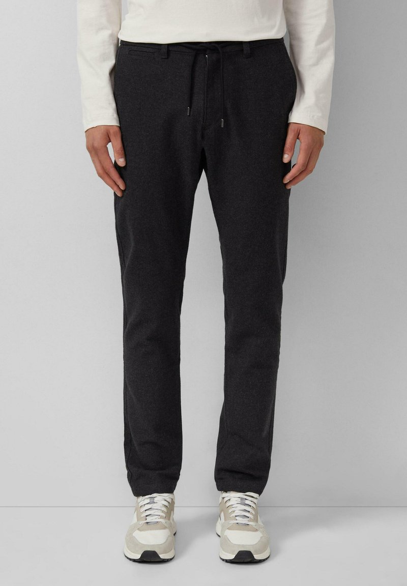 Donkergrijze tapered broeken van een zachte stof. Voorzien van een elastische tailleband met trekkoord en zijzakken. Gecombineerd met lichte sneakers.