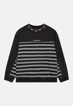 Fekete és szürke csíkos pulóver, bordázott nyakkal, fémes cérnával hímzett logóval és kontrasztos díszítéssel a nyakon.