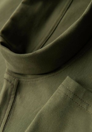Olivgrüner Pullover mit hohem Kragen, aus weichem Stoff gefertigt. Verfügt über sichtbare Nähte und ein kleines Taschendetail.