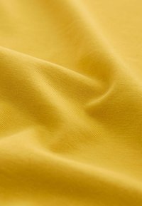Soft yellow fabric with fine knit texture shown in gentle folds and smooth surface details.