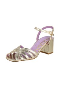 Sandal con tacón de metal dorado y diseño de punta abierta, con múltiples correas y un tacón cuadrado. La plantilla es de color púrpura claro.
