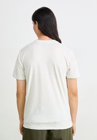 Short-sleeve, crew-neck t-shirt in off-white with a speckled pattern, made from soft fabric, shown from the back.