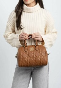 Bolso acolchado marrón con asas dobles, detalles en dorado y un logotipo. Una textura suave complementa el diseño ovalado compacto.