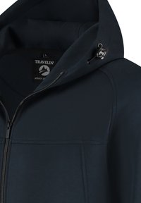 Veste à capuche bleu foncé en tissu doux, dotée d'une fermeture éclair à l'avant, de grandes poches et d'une capuche à cordon avec des accents métalliques.