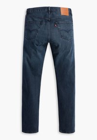 Jeans de ganga azul escuro com corte reto, apresentando uma etiqueta de couro na parte de trás da cintura e dois bolsos traseiros com detalhes de costura.