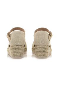 Wedges de espadrilles beige con una textura trenzada, tira al tobillo y tacón de yute apilado. Presenta una suela suave de color claro y herrajes dorados.