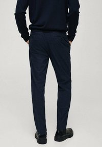 Pantaloni blu navy realizzati in tessuto testurizzato, con tasche laterali e taglio dritto. La vista posteriore mostra un design pulito e una vestibilità sartoriale.