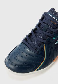 Baskets bleu marine en cuir texturé, avec des lacets ton sur ton et des accents contrastants en orange et teal. Comprend des perforations pour la ventilation et une semelle moulée.