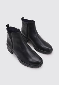 Botas de tobillo de cuero negro con una textura suave, cierre de cremallera lateral y un tacón cuadrado. Presenta tachuelas decorativas a lo largo del costado.