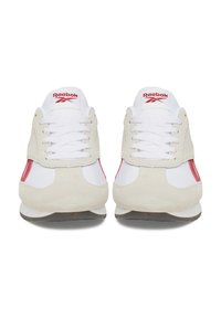 Białe sportowe sneakersy z czerwonymi akcentami, zamszowe i siatkowe materiały, zaokrąglony czubek, sznurowany krój oraz gumowa podeszwa. Logo Reebok na języku.