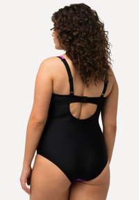 Maillot de bain noir avec bretelles ajustables, présentant une découpe ronde dans le dos et des accents violets. Texture lisse, conçu pour le confort et l'ajustement.
