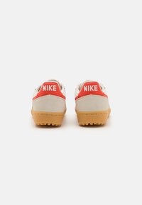 White and red Nike sneakers with a gum rubber sole, featuring a smooth upper and prominent logo on the heel.