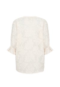 Vit blus i blommig spets med trekvartslånga puffärmar och volangkantade ärmslut, visad bakifrån mot en vit bakgrund.