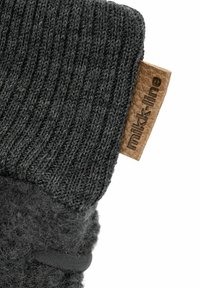 Graue gestrickte Fäustlinge mit einem gerippten Bündchen, einem weichen Stoffkörper und einem braunen Lederetikett mit einer eingravierten Aufschrift. Texturiert für Wärme und Komfort.
