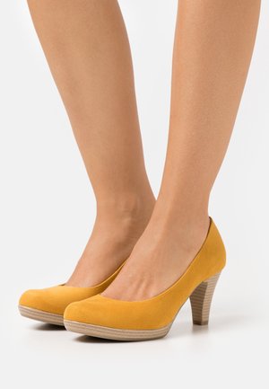 Gele suède pumps met afgeronde neuzen en een houtachtige, gestructureerde hak. Glad oppervlak en glanzende afwerking.