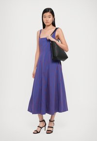 Blue and purple vertically striped sleeveless dress with a flared skirt, paired with a black handbag and strappy heeled sandals.