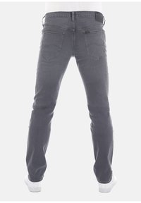 Jeans de mezclilla gris con corte slim, con bolsillos traseros y una cinturilla con marca, mostrados desde la parte trasera sobre un fondo liso.